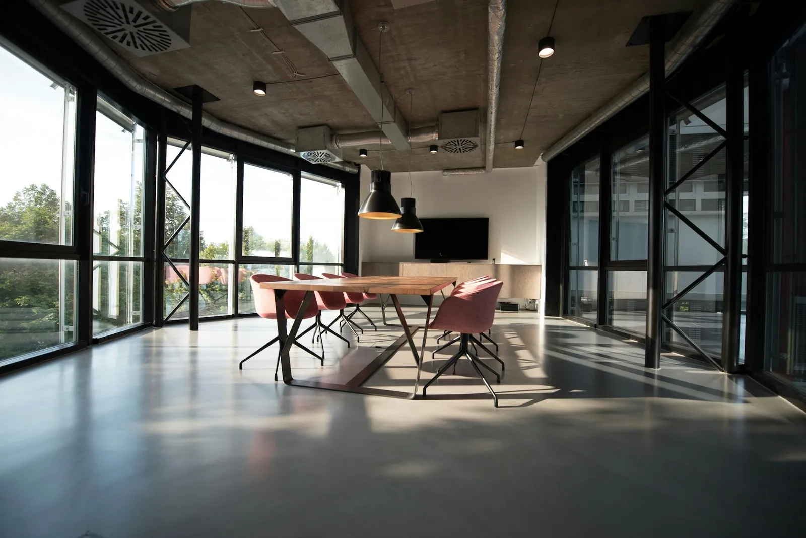 An empty modern office with vacated chairs around a meeting table, representing cybersecurity industry layoffs and restructuring