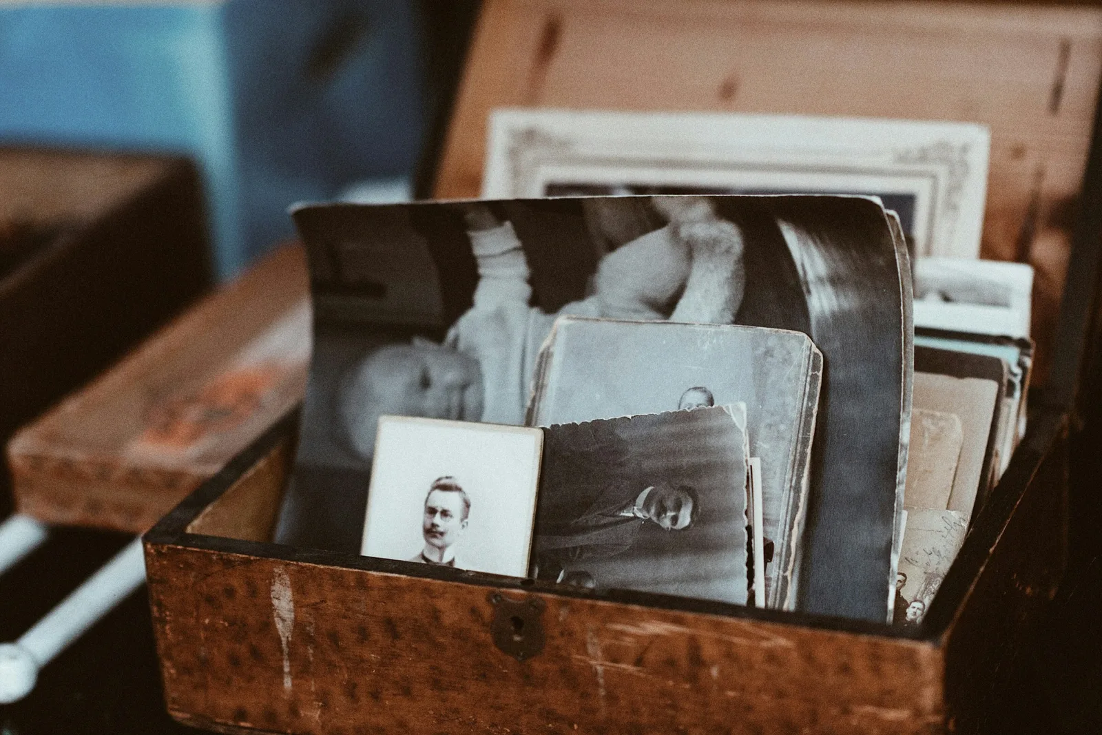 An open wooden chest filled with old black and white photographs and memorabilia
