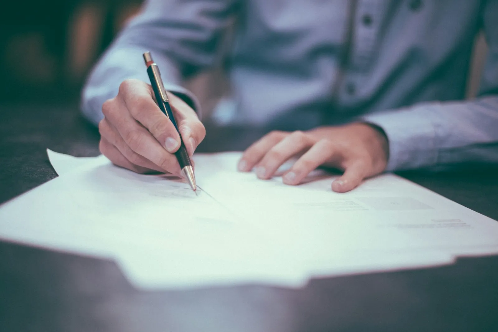 A professional signing a document at a desk with a pen