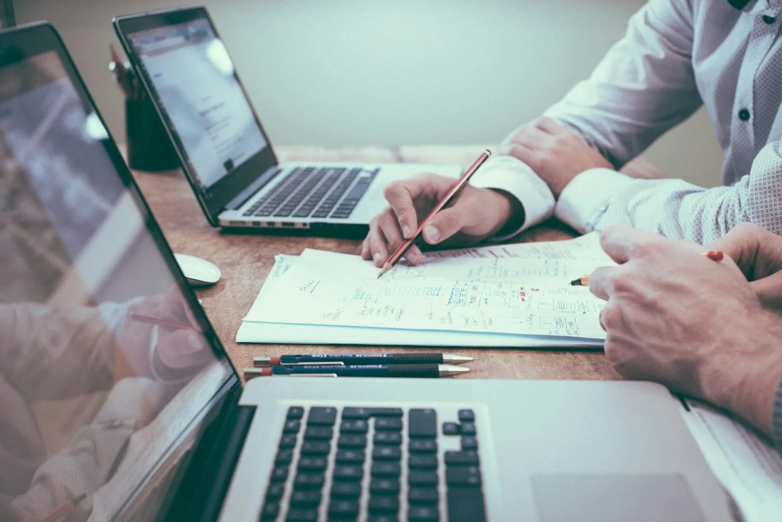 Two professionals reviewing printed charts and strategy documents at a desk